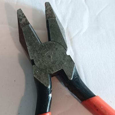 Red handled pliers with a 12' tape measure