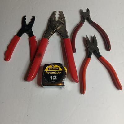 Red handled pliers with a 12' tape measure