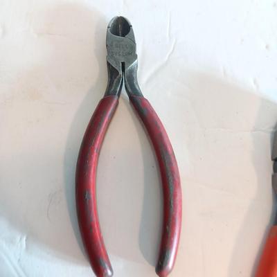 Red handled pliers with a 12' tape measure