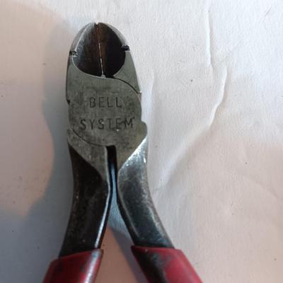 Red handled pliers with a 12' tape measure