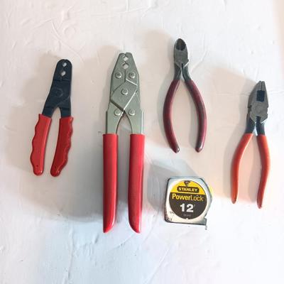 Red handled pliers with a 12' tape measure