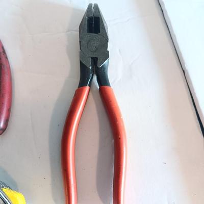 Red handled pliers with a 12' tape measure
