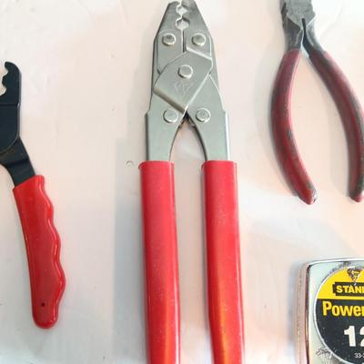 Red handled pliers with a 12' tape measure