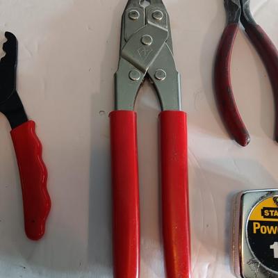 Red handled pliers with a 12' tape measure