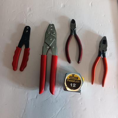 Red handled pliers with a 12' tape measure