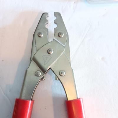 Red handled pliers with a 12' tape measure
