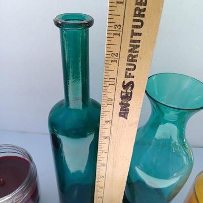 Colored bottle and vase with two scented candles in jars