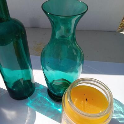 Colored bottle and vase with two scented candles in jars