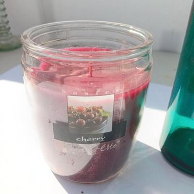 Colored bottle and vase with two scented candles in jars