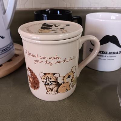 A VARIETY OF COFFEE CUPS AND A CARAFE