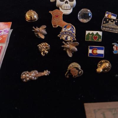 A COLLECTION OF PINS, PATCHES, WOODEN CARD AND WIND UP SKELETON