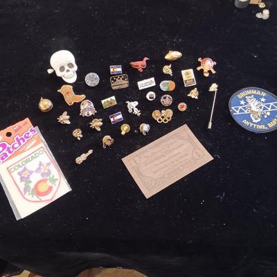 A COLLECTION OF PINS, PATCHES, WOODEN CARD AND WIND UP SKELETON