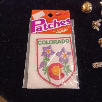 A COLLECTION OF PINS, PATCHES, WOODEN CARD AND WIND UP SKELETON