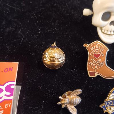 A COLLECTION OF PINS, PATCHES, WOODEN CARD AND WIND UP SKELETON