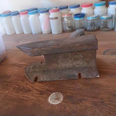 PLASTIC BOTTLES OF HARDWARE AND A HOMEMADE ANVIL
