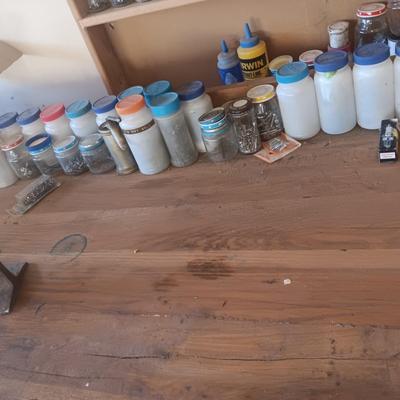 PLASTIC BOTTLES OF HARDWARE AND A HOMEMADE ANVIL