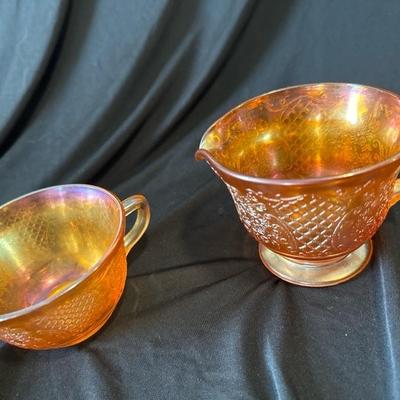 Sale Photo Thumbnail #793: This marigold carnival glass cup and creamer set have beautiful floral and lattice patterns which is also known as Normandie. It was produced by Federal glass from 1933 to 1940. Both are in very good condition, No chips or cracks. 

Beautiful set for use 