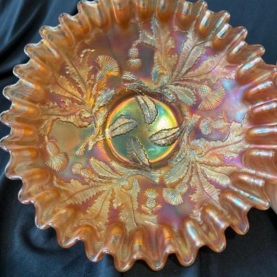 Sale Photo Thumbnail #804: This listing is for a vintage Fenton marigold carnival glass bowl that has the Thistle pattern on it. The bowl measures around 8 and 1/4 inches wide and stands around 2 and 1/2 inches tall. The bowl is in excellent condition with no cracks or chips. 

We 
