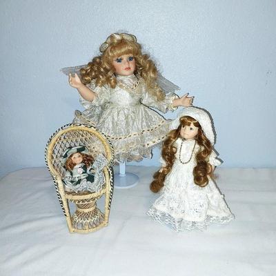 THREE PORCELIN DOLLS WITH WICKER CHAIR