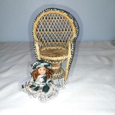 THREE PORCELIN DOLLS WITH WICKER CHAIR
