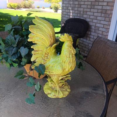 A LARGE CERAMIC ROOSTER AND A FAUX PLANT IN A BURLAP WRAPPED CONTAINER