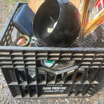 Black plastic milk crate with various items