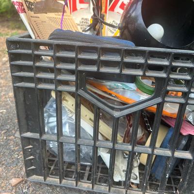 Black plastic milk crate with various items