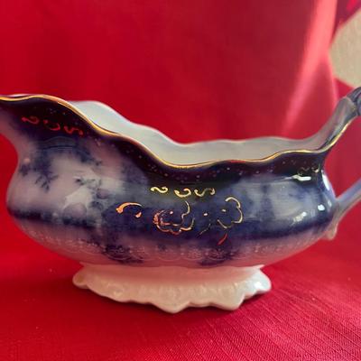 Beautiful, gold, trimmed blue, and white gravy boat along with over variety of saucers, dipping plates, and salad plates