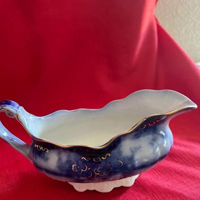 Beautiful, gold, trimmed blue, and white gravy boat along with over variety of saucers, dipping plates, and salad plates