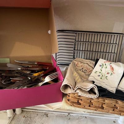 Box of eating utensils, several different sets, candles, silverware holder, and variety and doilies