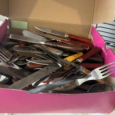 Box of eating utensils, several different sets, candles, silverware holder, and variety and doilies