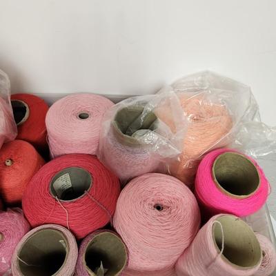 18 cones of yarn in pinks