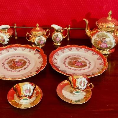 Porcelain tea set with Victorian figures and gold trim, teapot, sugar with lid, creamer, waste bowl, two tea cups and saucers, plus Cale...