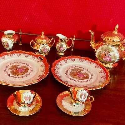 Porcelain tea set with Victorian figures and gold trim, teapot, sugar with lid, creamer, waste bowl, two tea cups and saucers, plus Cale...