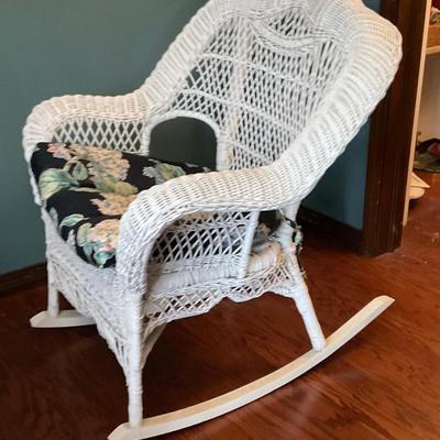 White wicker rocking chair, has floral cushion, some damage shown in pictures