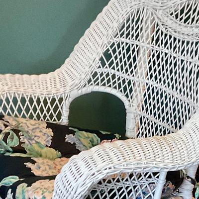 White wicker rocking chair, has floral cushion, some damage shown in pictures
