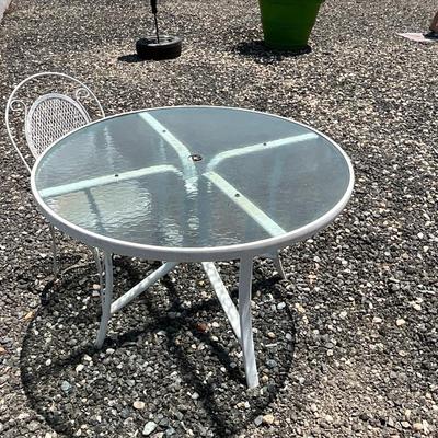 Lot# 190 Round Patio Glass Top Table with a Single White Wrought Iron Chair
