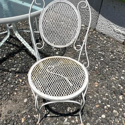 Lot# 190 Round Patio Glass Top Table with a Single White Wrought Iron Chair