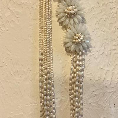 Long necklace has white beads and large white flowers