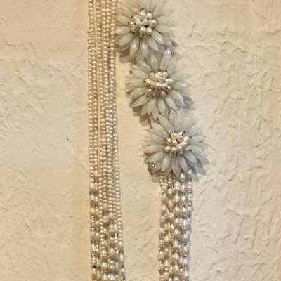 Long necklace has white beads and large white flowers
