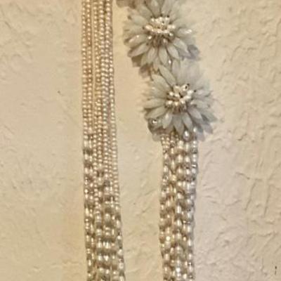 Long necklace has white beads and large white flowers
