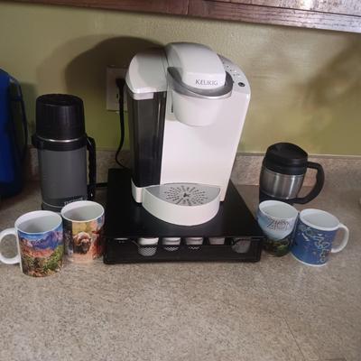 KEURIG SINGLE CUP COFFEE MAKER, PODS W/HOLDER, MUGS AND THERMOS