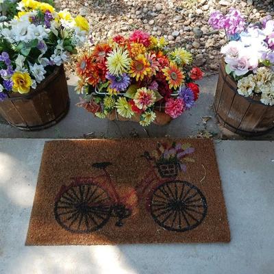 2 PLASTIC WHISKEY BARREL LIKE PLANTERS, BASKET OF FAUX FLOWERS AND DOOR MAT