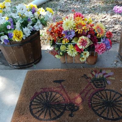 2 PLASTIC WHISKEY BARREL LIKE PLANTERS, BASKET OF FAUX FLOWERS AND DOOR MAT