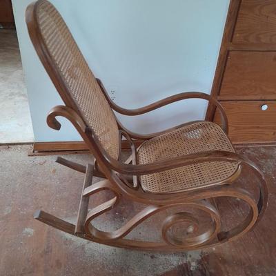 Wood framed wicker seat rocking chair with tall black lamp