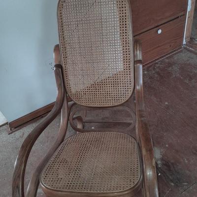 Wood framed wicker seat rocking chair with tall black lamp