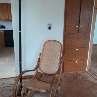 Wood framed wicker seat rocking chair with tall black lamp
