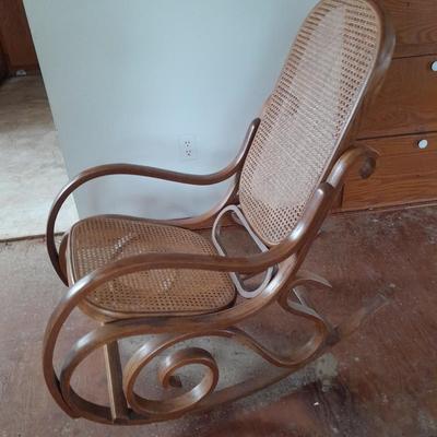 Wood framed wicker seat rocking chair with tall black lamp