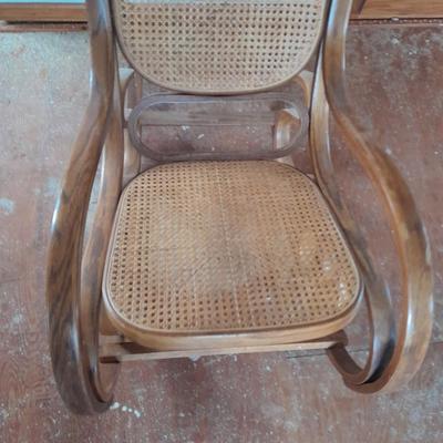 Wood framed wicker seat rocking chair with tall black lamp