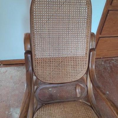 Wood framed wicker seat rocking chair with tall black lamp